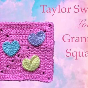 May include: A pink crochet granny square with three crocheted hearts in different colours: light blue, purple, and yellow. The text "Taylor Swift Lover Granny Square" is written above the square.
