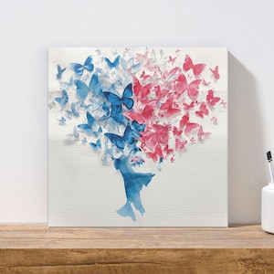 May include: A square canvas art print features a watercolor design of a silhouette with a head composed of blue and pink butterflies. The artwork is displayed on a wooden surface.