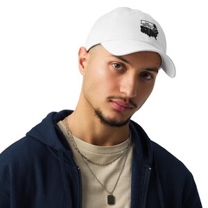 May include: White baseball cap with a curved brim. The cap features a black graphic of the United States map with the word "AMERICA" above it. The cap is made of a soft material and has an adjustable strap.