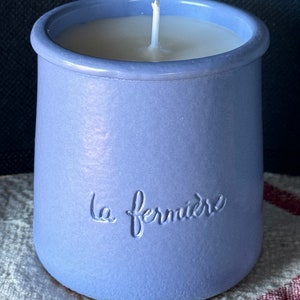 May include: A lavender ceramic candle jar with a white candle and the text "la fermiere" embossed on the side.