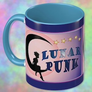 May include: A ceramic mug with a light blue handle and interior. The exterior features a graphic of a black silhouette of a person sitting on a crescent moon against a pink circle. The text LUNAR PUNK is printed in dark blue with five yellow stars above.