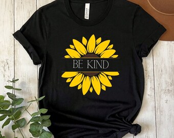 May include: Black t-shirt with a yellow sunflower graphic and the text "BE KIND" in a white banner.