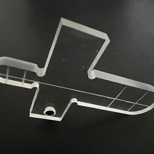 Pu&ograve; includere: Un modello in plastica trasparente a forma di croce con un foro al centro. Il modello ha linee di griglia ed &egrave; progettato per l'artigianato o progetti fai-da-te.