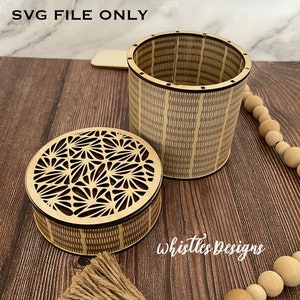 Puede incluir: Una caja de madera con un patrón geométrico en la tapa y los lados. La tapa está abierta y el interior de la caja es visible. La caja está hecha de madera clara y tiene un acabado natural.