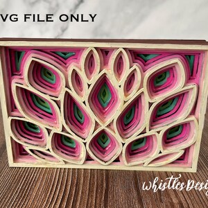 May include: A layered papercraft design with a pink, green, and cream color scheme. The design features a series of overlapping leaves and petals, creating a three-dimensional effect. The design is framed in a cream-colored frame.