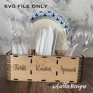 May include: A wooden utensil organizer with sections labeled "Forks", "Knives", and "Spoons". The organizer holds clear plastic forks, spoons, and white knives. A paper plate with a blue floral design is visible in the background. The text "SVG FILE ONLY" is at the top.