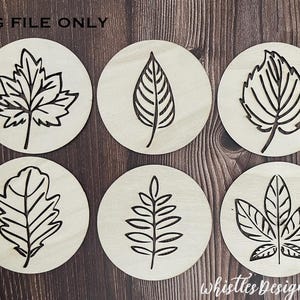 May include: Six wooden coasters with different leaf designs. Each coaster features a black outline of a leaf on a natural wood background.