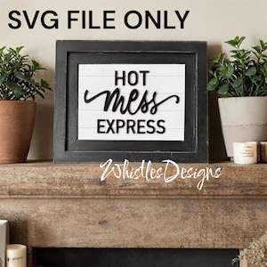 Puede incluir: Un letrero enmarcado en negro con las palabras "HOT MESS EXPRESS" en escritura negra. El letrero está sobre un fondo blanco con listones de madera horizontales. El texto "SVG FILE ONLY" está en la parte superior. El letrero está sobre una repisa de madera.