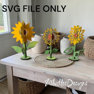 May include: Three wooden sunflower decorations with yellow petals, green stems and leaves, and brown centres. The sunflowers are displayed on a light-coloured wooden table. The text "SVG FILE ONLY" is at the top of the image.