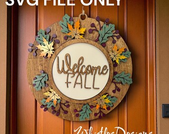 Puede incluir: Corona de otoño de madera con el texto "Welcome Fall" en el centro. La corona está decorada con hojas y bayas de colores. El texto "SVG FILE ONLY" está en la parte superior y "Whistles Designs" en la parte inferior.