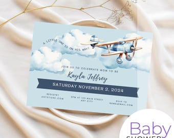 May include: Blue and white baby shower invitation with a watercolor illustration of a small airplane flying through clouds. The text reads "A little one is on his way!" and "Join us to celebrate mom to be Kayla Jeffrey Saturday November 2, 2024".
