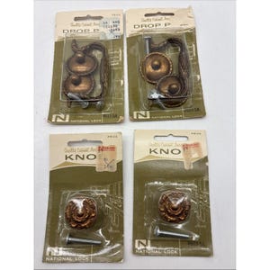 May include: Four vintage cabinet hardware sets. Two sets are labeled "DROP P" and two are labeled "KNO". The hardware is bronze-colored and includes pulls and knobs with screws, all on original packaging.