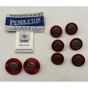 May include: A collection of red buttons with a gold emblem, alongside a Pendleton label and a size 12 tag. The label reads "Pendleton Classic 100% Virgin Wool" and "Made in U.S.A."