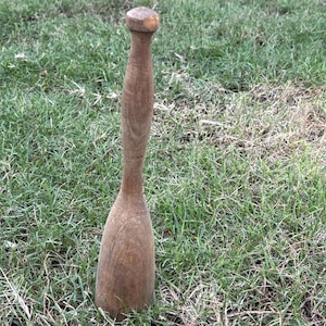 May include: A wooden muddler with a rounded top and a long, slender handle. The muddler is made of a light brown wood and has a smooth finish. It is designed for mixing ingredients in cocktails or other beverages.