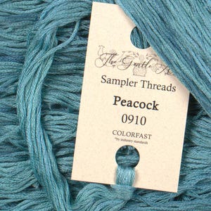 May include: A skein of teal blue embroidery floss with a label that reads "The Gentle Art Sampler Threads Peacock 0910 Colorfast *by industry standards"