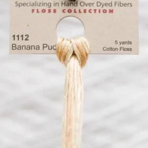 May include: A skein of 5 yards of Banana Puc cotton floss, a light beige color with a subtle shimmer. The floss is wound around a card with the text "Specializing in Hand Over Dyed Fibers FLOSS COLLECTION 1112 Banana Puc 5 yards Cotton Floss".