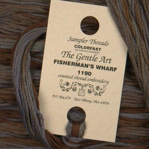 May include: A brown and beige label with the text "Sampler Threads COLORFAST by industry standards The Gentle Art FISHERMAN'S WHARF 1190 counted thread embroidery P.O. Box 670 New Albany, Ohio 43054"