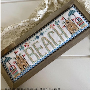 May include: Cross-stitch artwork in a wooden frame. The design features the word "BEACH" in teal and tan cross-stitch, with beach-themed illustrations. The artwork is framed with a blue and white gingham border and a wooden frame. The text "BASED ON ORIGINAL CHALK ART BY PRISCILLA BLAIN" is at the bottom.