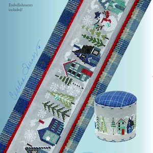 May include: A cross stitch pattern for a winter scene with the text "FROSTY tiny town". The pattern features a row of houses, trees, and snow. The pattern is surrounded by a blue and white plaid border. Embellishments are included.