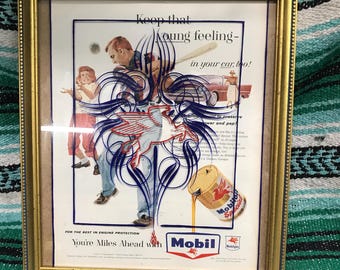 Anuncio de revista de aceite Mobil de la década de 1950 enmarcado con rayas finas pintadas a mano en el cristal.