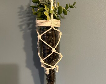 Glass bottle planter with macramé holder and greenery accent