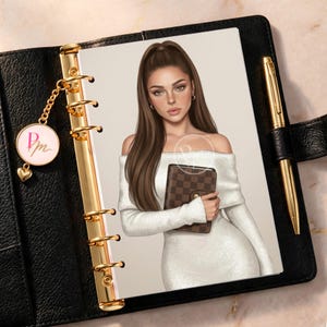 May include: A black leather planner with gold rings, a gold pen, and a circular charm featuring the letters PM. The planner contains an illustration of a person with long brown hair wearing an off-the-shoulder white dress and holding a brown checkered wallet.