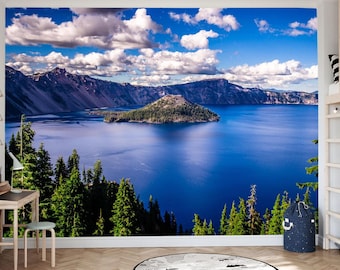 May include: A scenic wall mural showing a mountain range, a lake, and an island under a bright blue sky with fluffy white clouds. The lake is a deep blue, and the island is covered in green trees. The mural creates a serene and natural atmosphere.