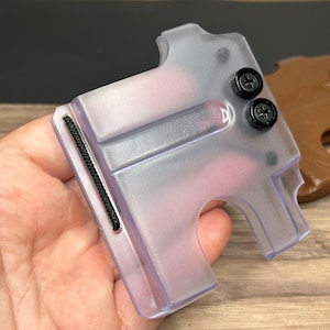 Puede incluir: Un porta tarjetas de pl&aacute;stico transparente con una banda el&aacute;stica negra y dos tornillos negros. El porta tarjetas tiene una ranura para tarjetas y un peque&ntilde;o agujero para un cord&oacute;n.
