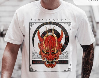 May include: White t-shirt with a red and black Japanese demon mask graphic. The graphic is surrounded by a black circle and Japanese characters. The text "WHITE" is in the upper right corner of the image.