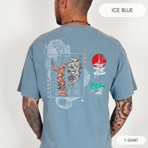 May include: A light blue t-shirt with a graphic print of a Japanese demon mask, a pagoda, a bonsai tree, and a dragon. The text "ICE BLUE" is in the top right corner and "T-SHIRT" is in the bottom right corner.