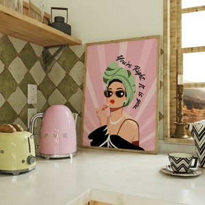 May include: Pink and black framed print with a woman wearing sunglasses and a green headscarf. The text on the print reads "You're Right, It is You."