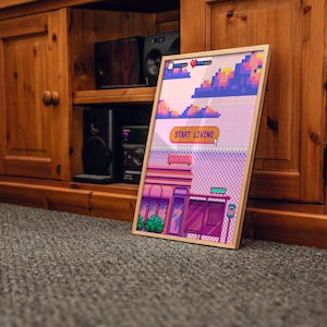 May include: A framed pixel art print with a pink, purple, and blue color scheme. The print depicts a building with a sign that reads "Start Living".