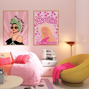 May include: Two framed posters on a pink wall. The poster on the left features a woman with sunglasses and a green turban, with the text "You're Right It is a Big Deal". The poster on the right features a blonde woman with the text "Barbie for President".