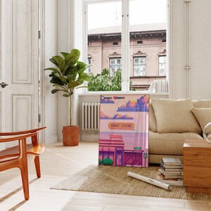 K&ouml;nnte beinhalten: Ein Pixel-Kunstdruck mit einer rosafarbenen und violetten Stadtlandschaft mit dem Text "Start Living" im Videospiel-Stil.