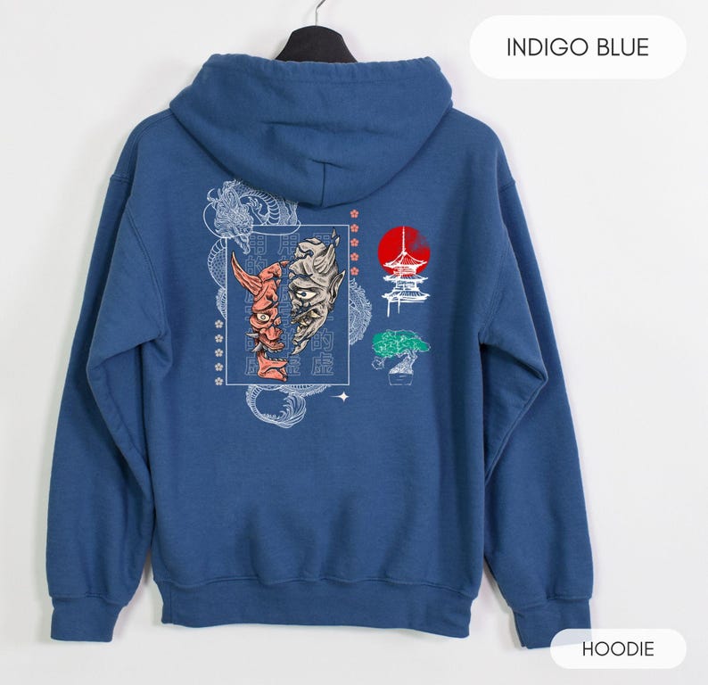 May include: Indigo blue hoodie with a graphic print of a Japanese demon mask, a pagoda, and a bonsai tree. The text "INDIGO BLUE" is printed in white at the top of the image. The word "HOODIE" is printed in white at the bottom of the image.
