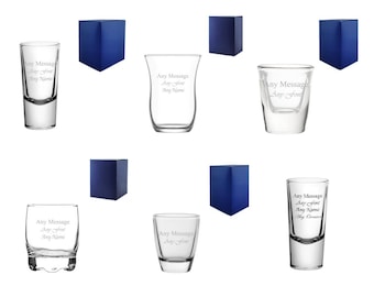 May include: An assortment of clear shot glasses with the text "Any Message, Any Font, Any Name" etched on them. The shot glasses are displayed with several small, dark blue gift boxes. The glasses vary in shape and size.