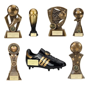 Peut inclure: Une collection de trophées sur le thème du football et une chaussure de football noire et dorée. Les trophées sont de couleur bronze et présentent des ballons de football, des chaussures et des étoiles. Chaque trophée a un espace pour la gravure.