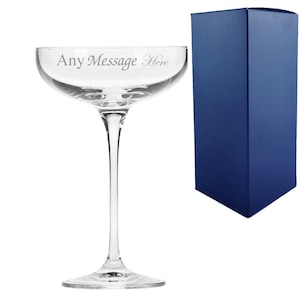May include: A clear glass champagne coupe with a stem and a wide bowl. The glass is engraved with the text "Any Message Here". The glass is packaged in a blue box.