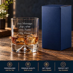 May include: A clear glass tumbler containing amber liquid and ice cubes, featuring the engraved text Any Message, Any Font, Any Name, Any Occasion. A solid dark blue rectangular box stands next to the glass on a wooden surface.