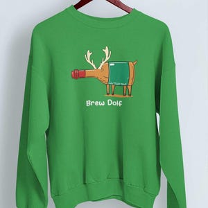 May include: Green sweatshirt with a cartoon reindeer made out of a beer bottle. The reindeer has antlers and a red nose. The text "Brew Dolf" is printed below the reindeer.