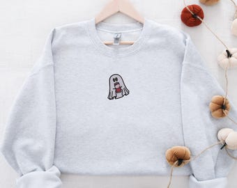 May include: A gray sweatshirt with a small embroidered ghost holding a cup of coffee. The ghost has a surprised expression on its face.