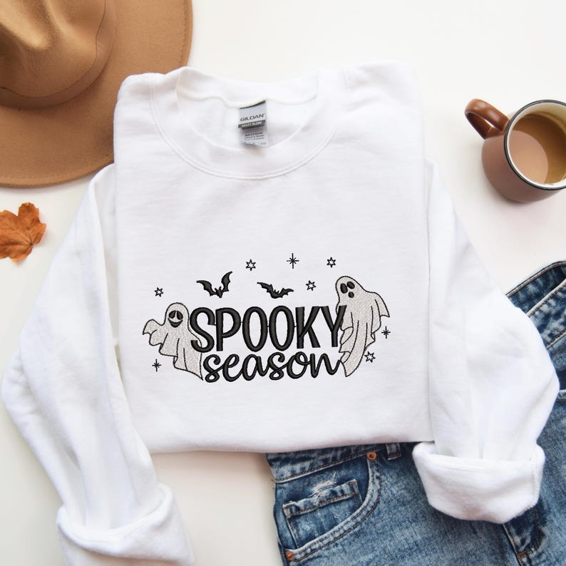 May include: White sweatshirt with a black embroidered design of ghosts and bats with the text "Spooky season".