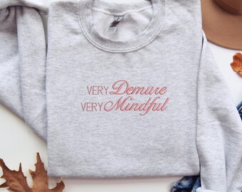May include: Gray sweatshirt with the text "Very Demure Very Mindful" in pink.