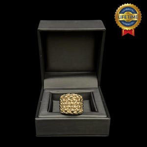 May include: A gold ring with a textured design, displayed in a black velvet ring box. The box has a "Lifetime Guarantee" label.