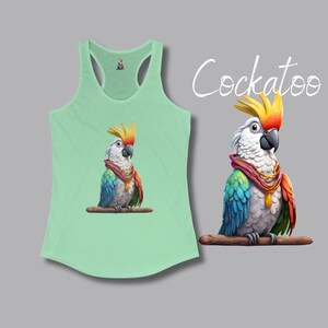 May include: A light green tank top featuring a colorful illustration of a cockatoo. The bird has white feathers, a yellow crest, and a red and orange scarf. The word "Cockatoo" is written in white script.