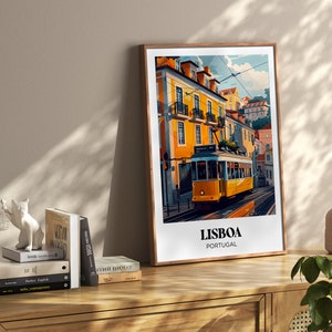 May include: A framed illustration of a yellow tram traveling through a street in Lisbon, Portugal. The illustration features colorful buildings and a blue sky. The text "LISBOA PORTUGAL" is printed below the tram.