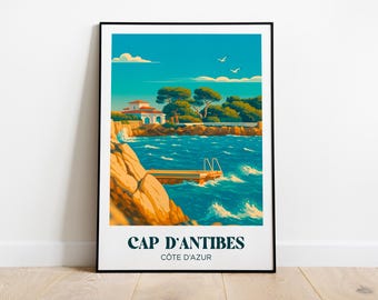 Puede incluir: Una impresión artística enmarcada de Cap d'Antibes, Côte d'Azur. La obra representa una escena costera con un edificio, árboles y una plataforma de buceo sobre agua turquesa. El cielo es azul brillante con algunas nubes blancas y dos gaviotas.