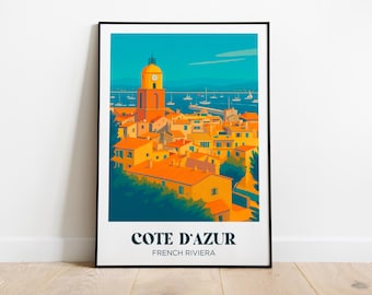 Puede incluir: Una impresión artística enmarcada de la Riviera francesa. La imagen presenta un pueblo costero con tejados naranjas, una torre del reloj y veleros en el mar turquesa. El texto "COTE D'AZUR FRENCH RIVIERA" está impreso en la parte inferior.