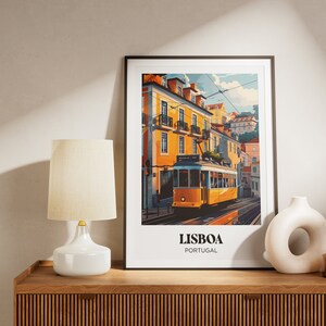 May include: A framed print of a yellow tram traveling up a hill in Lisbon, Portugal. The print features colorful buildings and a blue sky. The text "LISBOA PORTUGAL" is at the bottom of the print.