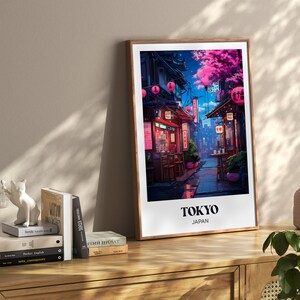 Pu&ograve; includere: Una stampa incorniciata di un'illustrazione colorata di una strada a Tokyo, Giappone. La strada &egrave; fiancheggiata da edifici e negozi, e ci sono persone che camminano. La stampa &egrave; in una cornice di legno e ha il testo "TOKYO GIAPPONE" in basso.